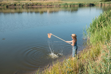 Child with a insect net catches frog