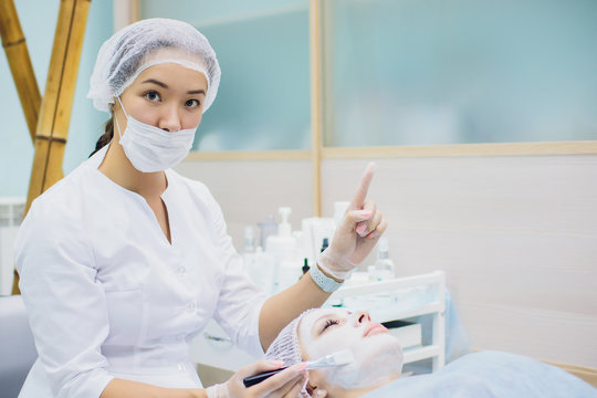 The doctor-cosmetologist makes a procedure of ultrasound facial cleaning of the skin of a beautiful, young woman in beauty salon, spa. Cosmetology and professional skin care.
