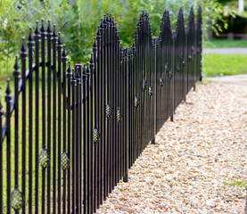 Black decorative metal fence, angular iron rods and curved upper part.