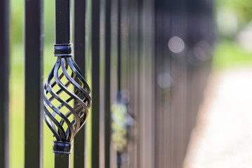 Black decorative metal fence, angular iron rods and curved upper part. Close-up of the decoration...