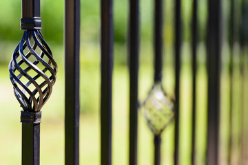 Black decorative metal fence, angular iron rods and curved upper part. Close-up of the decoration,...