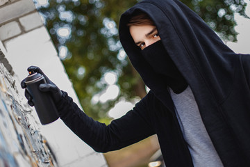 A young man with can spray in hand. Close-up.