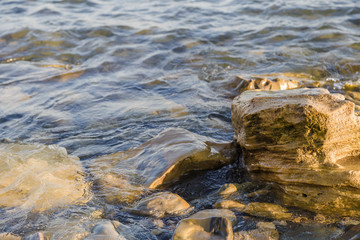 Sea waves are fighting against the big rocks on the shore.