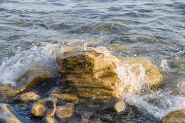 Sea waves are fighting against the big rocks on the shore.