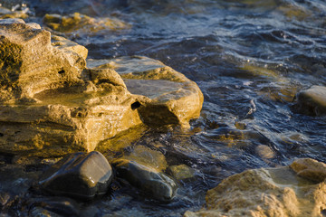 Sea waves are fighting against the big rocks on the shore.