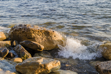 Sea waves are fighting against the big rocks on the shore.
