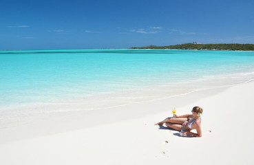 Fototapeta premium Girl with a glass of orange on the beach of Exuma, Bahamas