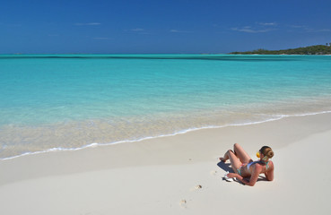 Fototapeta na wymiar Girl with a glass of orange on the beach of Exuma, Bahamas
