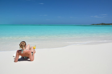 Fototapeta na wymiar Girl with a glass of orange on the beach of Exuma, Bahamas