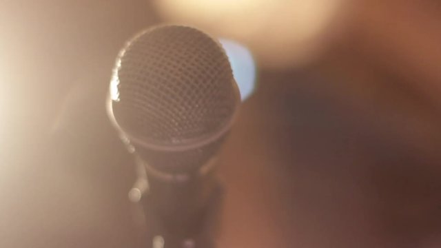 Left to right pan of microphone on stand in the dark with glowing lights