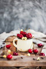 Fresh ripe cherries in a mug on rustic background