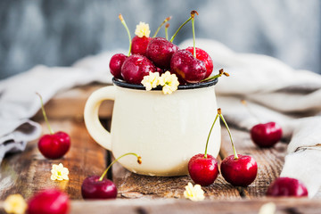 Fresh ripe cherries in a mug on rustic background