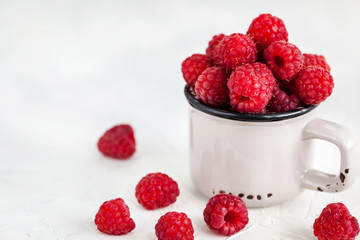 Fresh ripe raspberries in a mug on white