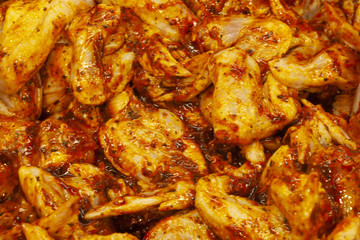 Raw chicken wings in marinade with pepper souse.