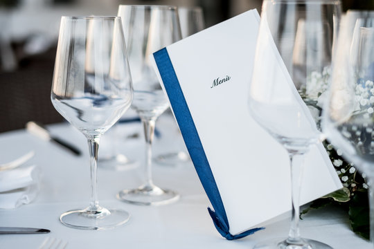 In un ristorante italiano, un elegante men&ugrave; che spunta fra bicchieri di vino su di una tavola imbandita per una cerimonia