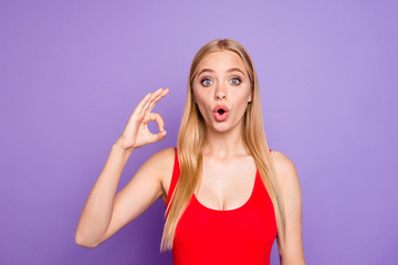 Attractive blonde girl wearing red swim suit shocked showing ok okay sign. Isolated over violet...