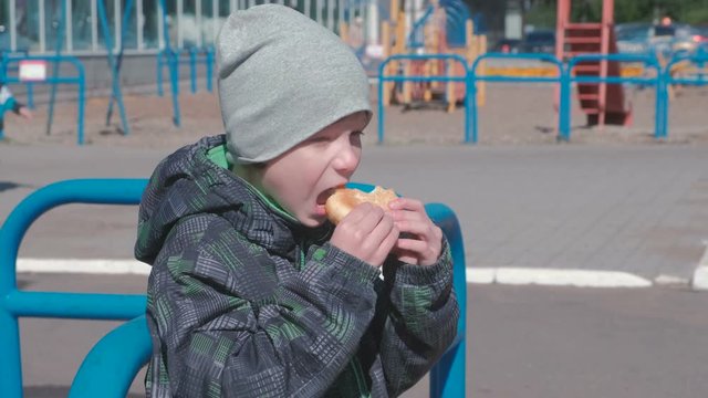 Boy eating a bun on the Playground.