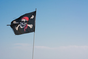Horizontal View of The Pirates' Jolly Roger Flag on Blue Sky Background
