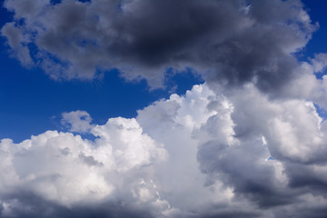 Blue sky with storm clouds. Rain clouds are illuminated by the rays of the setting sun.