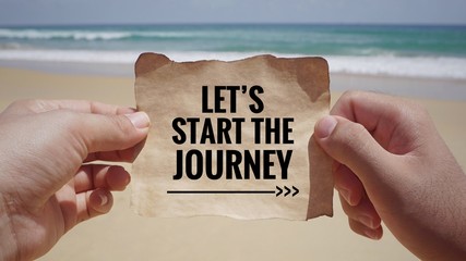 Motivational and inspirational quote - Hands holding a white piece of paper with text ‘Let’s start the journey’ on it. Vintage styled background.	