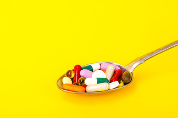 Tablets, capsules, pills in spoon on bright background. The concept of medicine and health