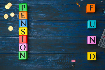 Cubes with text PENSION FUND and coins on wooden background