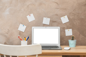 Laptop on desk against color wall in home office. Comfortable workplace