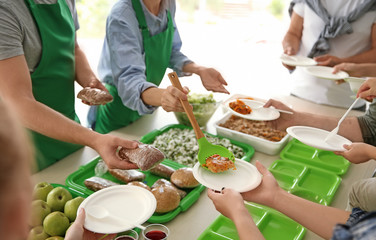 Volunteers serving food for poor people indoors