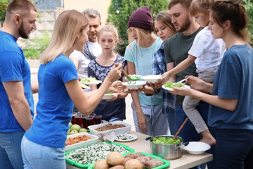 Volunteers serving food for poor people outdoors