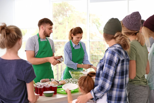Volunteers serving food for poor people indoors