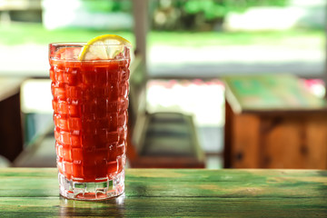 Glass of delicious cocktail with slice of lemon on table