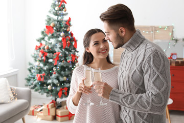 Happy young couple with glasses of champagne celebrating Christmas at home