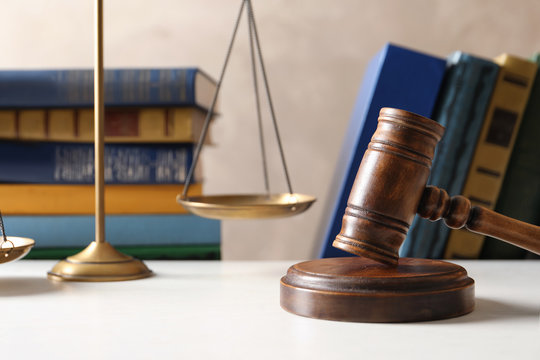 Wooden gavel with scales of justice and books on table against color background. Law concept