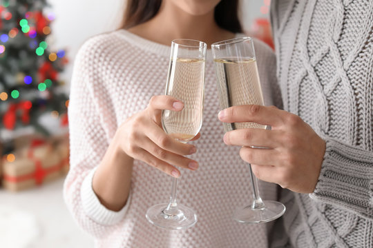 Happy young couple with glasses of champagne celebrating Christmas at home