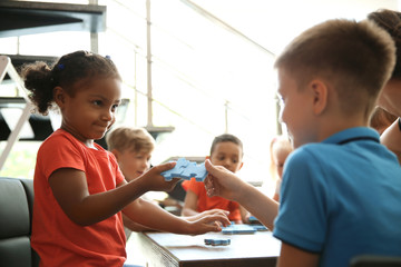 Little children holding puzzle pieces in hands, indoors. Unity concept