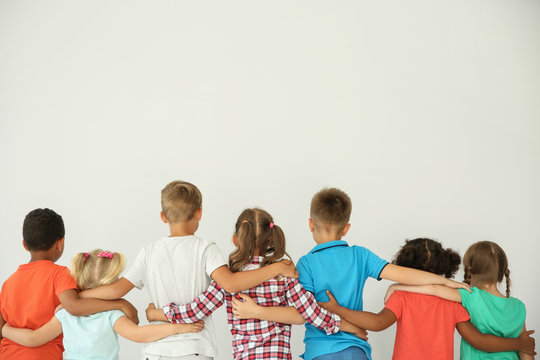 Little children hugging each other with hands on light background. Unity concept