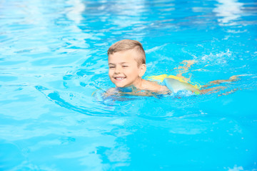 Fototapeta na wymiar Little boy in swimming pool on sunny day