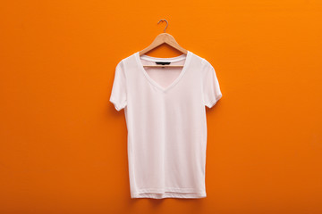 Hanger with blank t-shirt on color background. Mockup for design