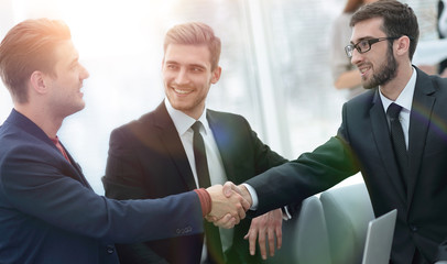 Partners concluding deal and shaking hands in the presence of team members