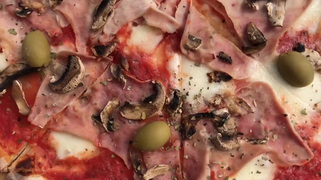 Slow motion close-up of steaming capricciosa pizza
