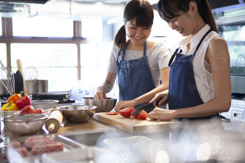 友人と食事を作る女性はとても楽しそうに会話をしながら野菜を切っている Wall Mural Monet