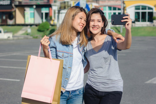 Attractive beautiful asian woman using a smartphone while shopping in the city. Happy young asian teenage at urban city while taking self portraits with her friends together with a smartphone.
