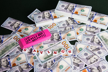 Obraz na płótnie Canvas Savings: Close up scattered US Dollars with message on pink eraser for really big mistakes. Budgeting and saving money early.