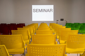 Ready to use rows of colorful chairs in conference room with words seminar on wall as projector screen