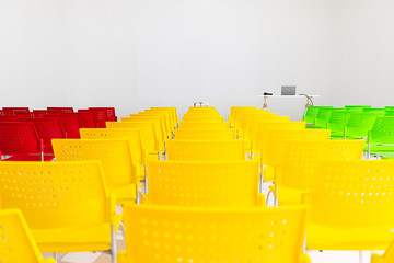 Ready to use rows of colorful chairs in conference room with projector and laptop on table, copy space on top area