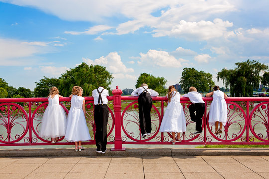 Children dressed up in a wedding party looking over a bridge