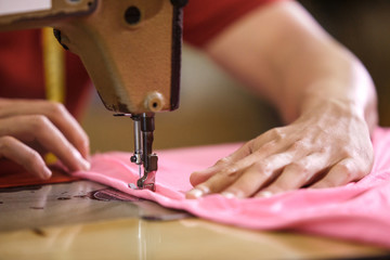 man's hands sewing on a sewing machine at a clothing factory