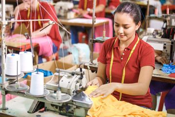 Seamstress in textile factory sewing with industrial sewing mach