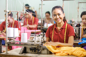 Seamstress in textile factory smiling while  sewing with industr
