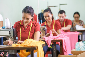 asian workers in garment factory sewing with industrial sewing m